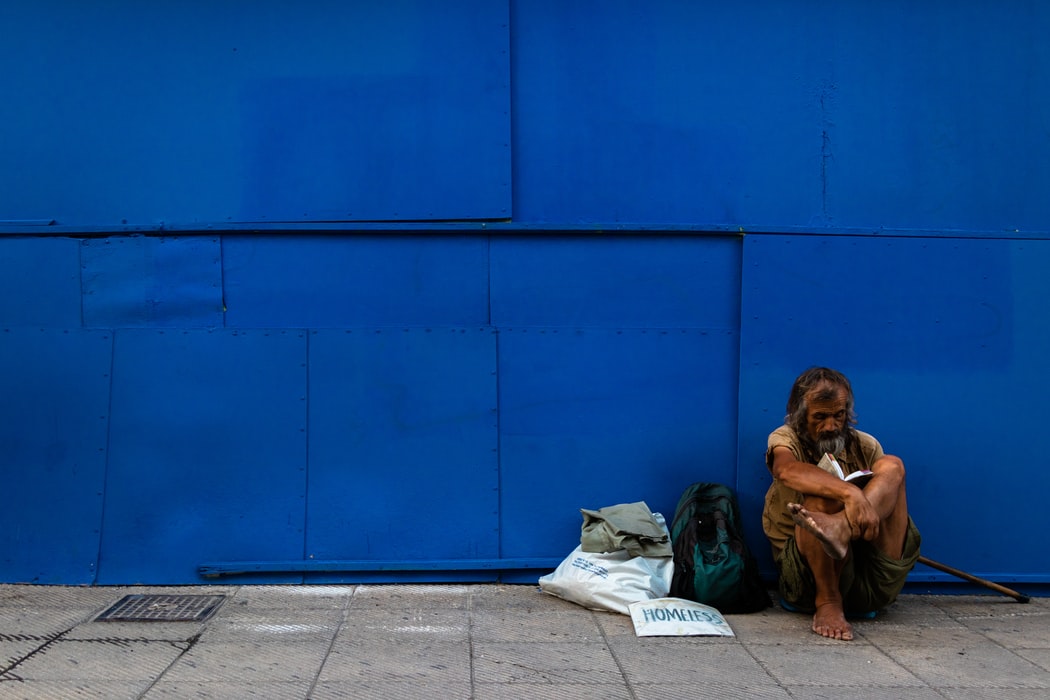 無家者在一面藍色的牆角坐著